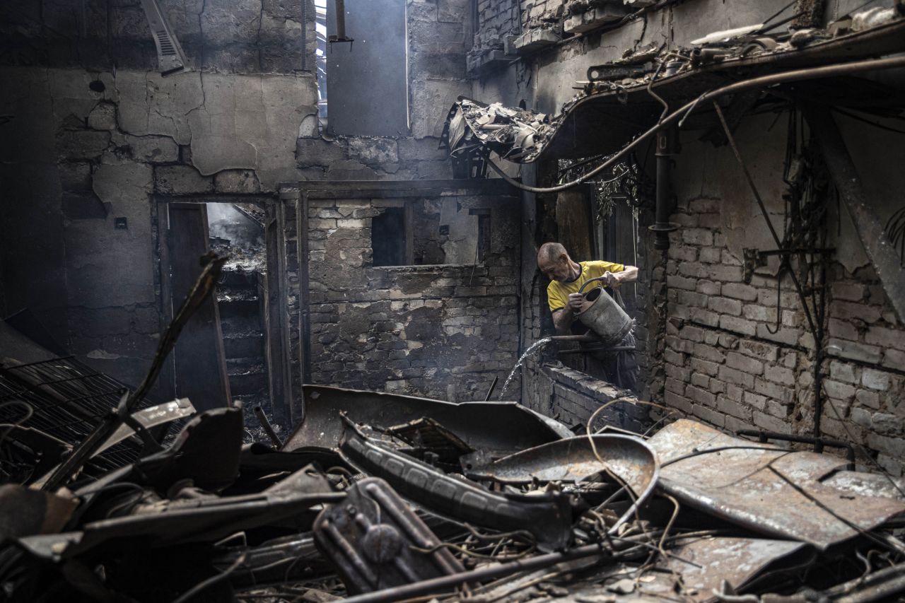 A man tries to extinguish a fire at a home in Ukraine's Donetsk region after a Russian airstrike on Tuesday, August 16.