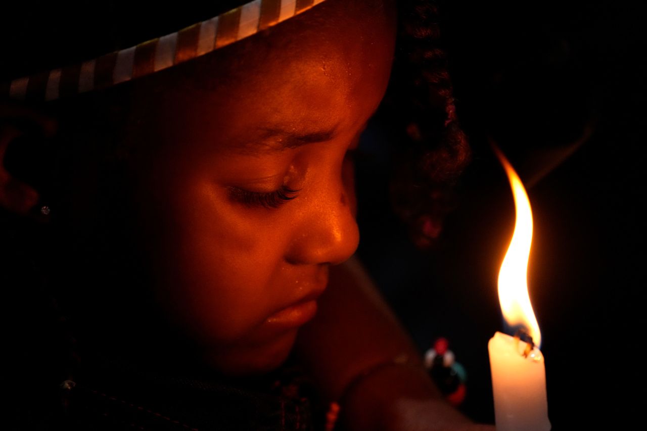A child holds a candle during a baptism ceremony in Goias, Brazil, on Monday, August 15. 