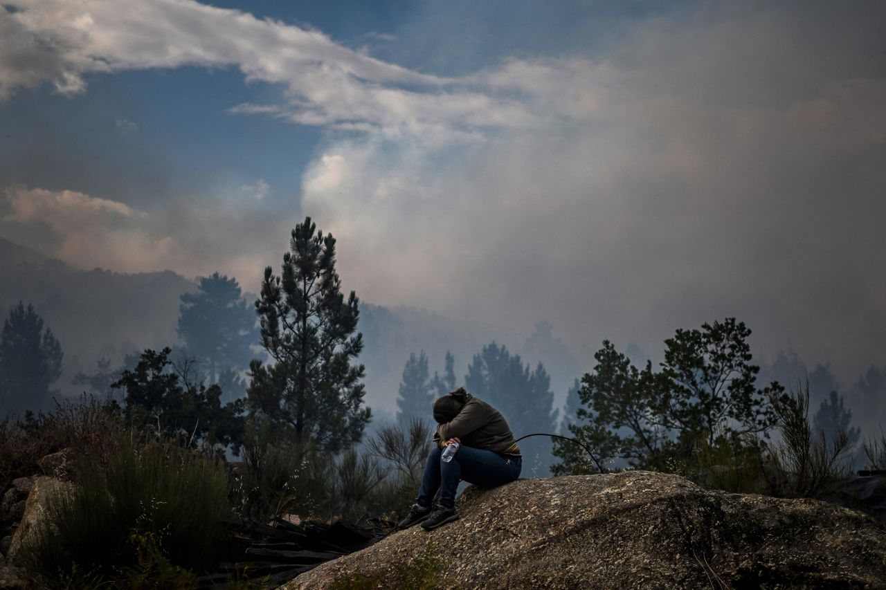 A woman cries as a wildfire advances toward her house and peach tree orchard in Orjais, Portugal, on Tuesday, August 16.