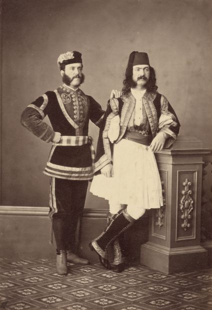 Two men in the traditional costumes of Turkey, Greece or the Balkans, circa 1870. The man on the right is wearing a white skirt known as a fustanella.