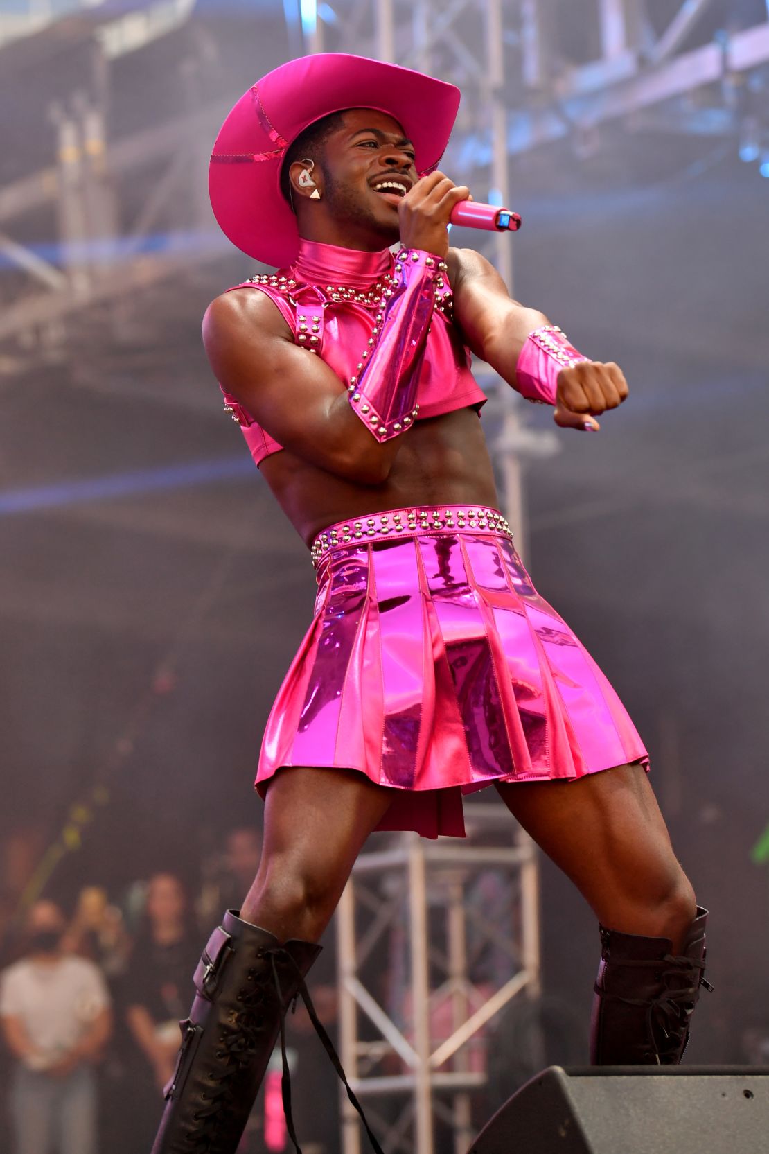 Lil Nas X wearing a metallic pink skirt during a concert. 