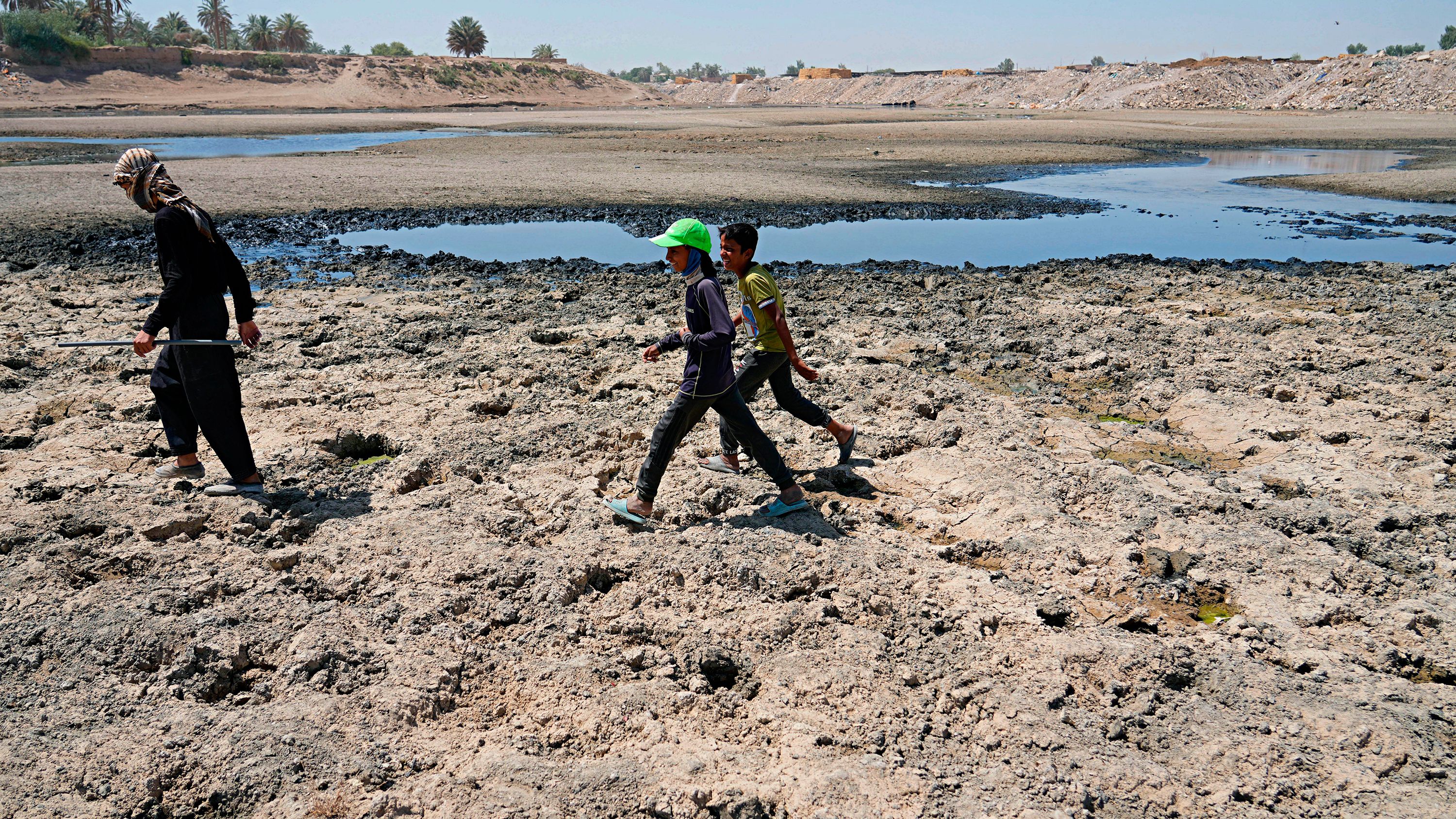 People cross the Diyala River, a tributary of the Tigris, where decreasing water levels this year have raised alarm among residents near Baghdad, Iraq, on June 29. 