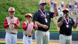 Jace Oliverson, center, father of Little Leaguer Easton Oliverson, holds Easton's medal, with another son, Brogan Oliverson (6) at his side, taking Easton's place on the championship team from Santa Clara, Utah before a baseball game against Nolensville, Tennessee., at the Little League World Series on Friday.