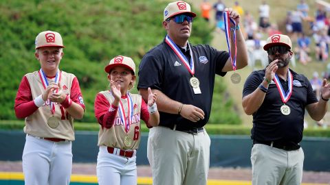 Jace Oliverson, center, father of Little Leaguer Easton Oliverson holds Easton's medal, with another son, Brogan Oliverson (6) at his side before a baseball game against Nolensville, Tennessee, at the Little League World Series on Friday. 