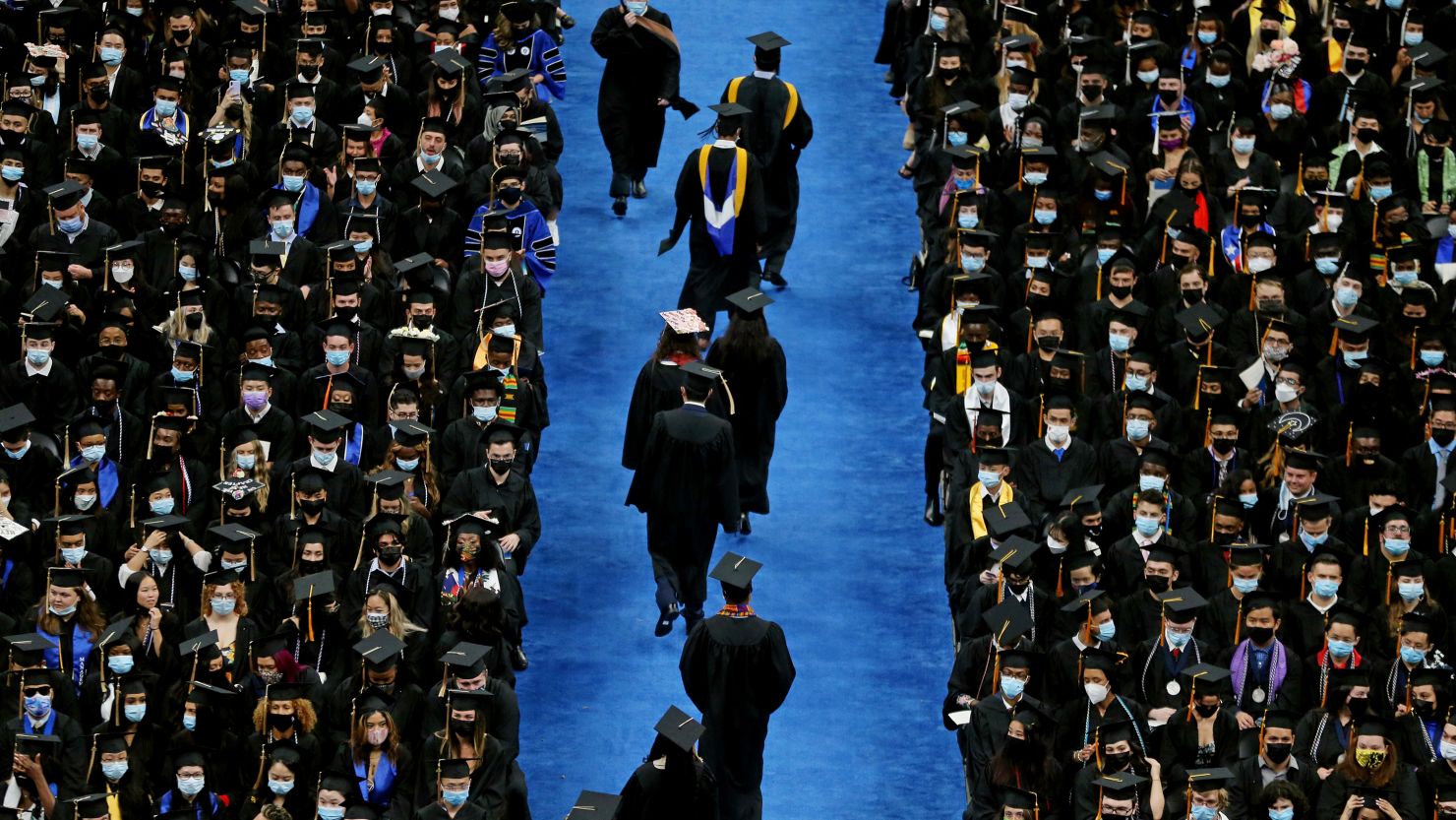 Graduates file down the aisle during a commencement ceremony at the University of Massachusetts Boston on August 26, 2021. 