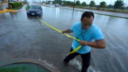 Mon Lun pulls a strap to his water-stalled car Monday before towing it out of receding flood waters in Dallas.
