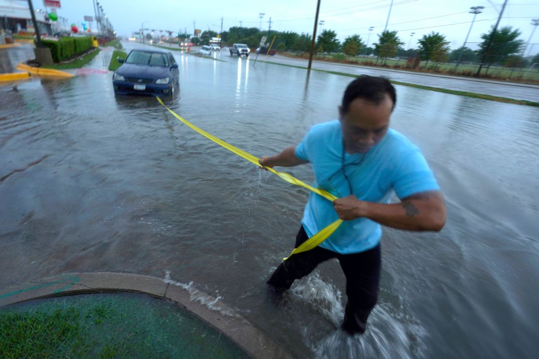 Mon Lun pulls a strap to his water stalled car Monday before towing it out of receding flood waters in Dallas.
