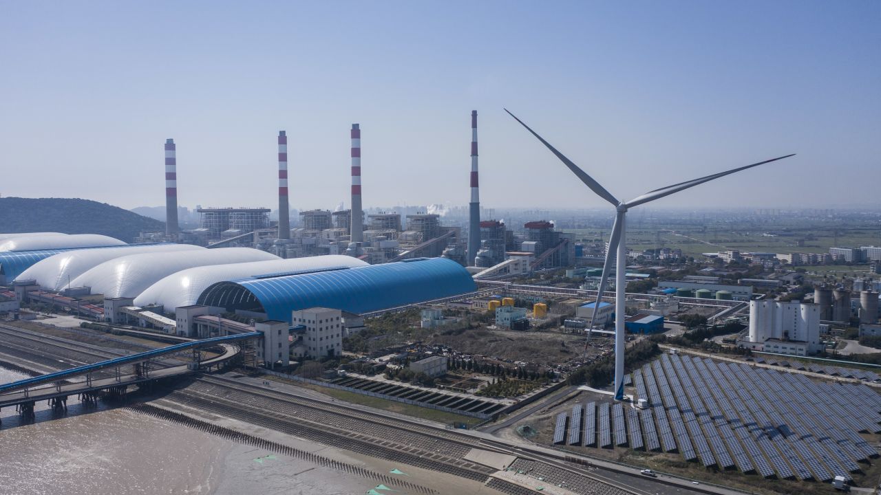 Photovoltaic panels at a solar farm and wind turbines near a coal fired power station in Jiaxing, Zhejiang province, China, on Friday, March 11, 2022.