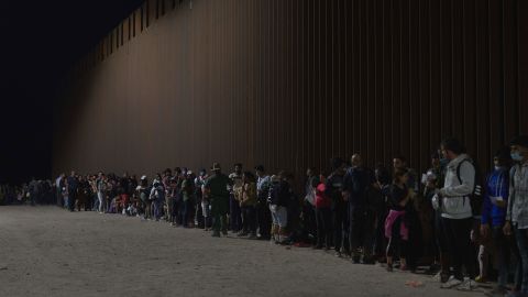  Migrants line up as they wait to be processed by US Border Patrol after illegally crossing the US-Mexico border in Yuma, Arizona in the early morning of July 11, 2022. (Photo by ALLISON DINNER/AFP via Getty Images)