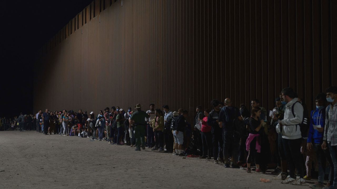 Migrants line up as they wait to be processed by US Border Patrol officials after illegally crossing the US-Mexico border in Yuma, Arizona, in the early morning of July 11, 2022.