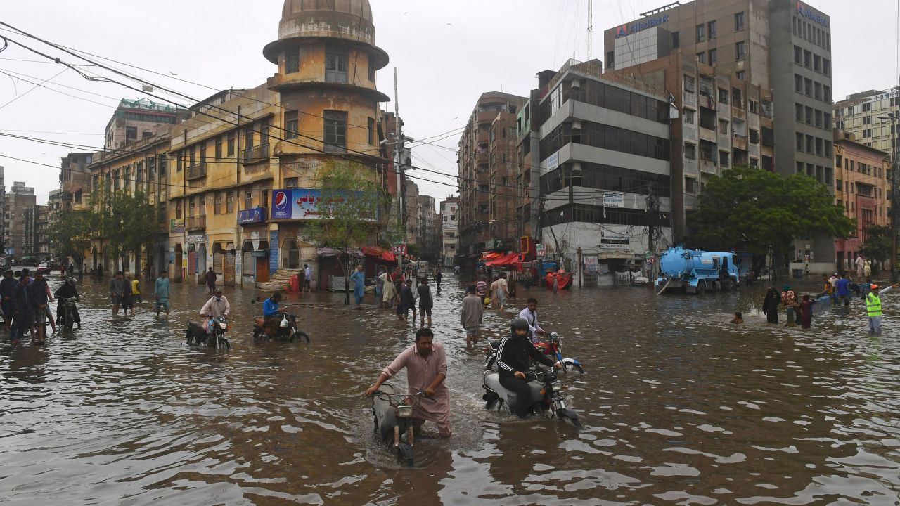 People wade across a flooded street after heavy monsoon rainfall in Karachi on July 25.
