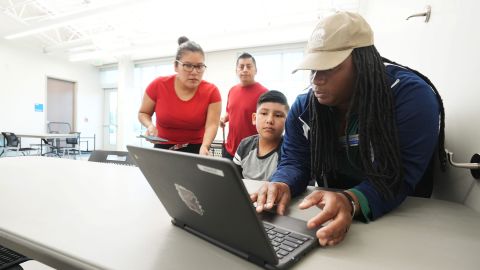 Columbus Recreation and Parks Department staffer Ambrosia Lamarr helps Asher Aquino, 11, log in at the Linden Community Center. Behind Asher are his parents, Antonio Bargas and Graciela Aquino.