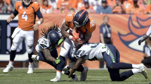 Denver Broncos running back Royce Freeman (center) gets taken down by Griffin (49) and his brother, Shaquill (26), at Broncos Stadium at Mile High.