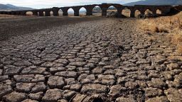 Part of the Guadiana river has dried up and gives way to dry land under the Puente de la Mesta medieval bridge in Villarta de los Montes, in the central-western Spanish region of Extremadura, on August 16, 2022. - Temperatures in Spain have been very high this summer with several unusual heat waves. Scientists say human-induced climate change is making extreme weather events including heatwaves and droughts more frequent and more intense.