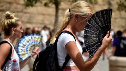 Two women use fans to fight the scorching heat during a heatwave in Seville on June 13, 2022. - Spain was today already in the grips of a heatwave expected to reach "extreme" levels, and France is bracing for one, too, as meteorologists blame the unusually high seasonal temperatures on global warming.