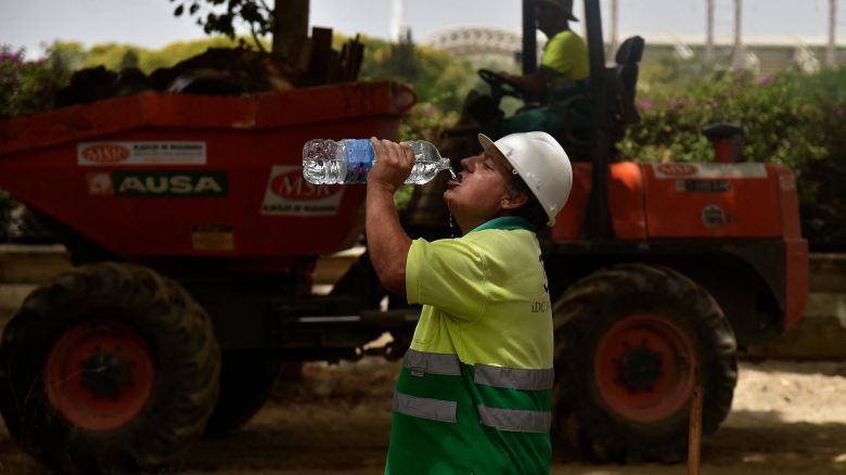 A construction worker drinks water to fight the scorching heat during a heatwave in Seville on June 13, 2022. - Spain was today already in the grips of a heatwave expected to reach "extreme" levels, and France is bracing for one, too, as meteorologists blame the unusually high seasonal temperatures on global warming.