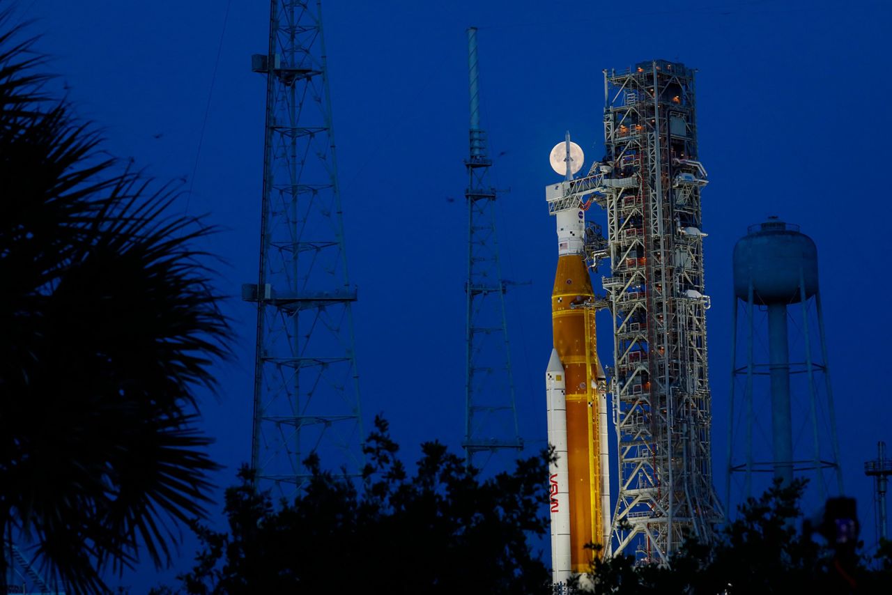 The moon peeks behind the Artemis I rocket in Cape Canaveral, Florida, on June 15, days before a wet dress rehearsal test of NASA's Space Launch System. 