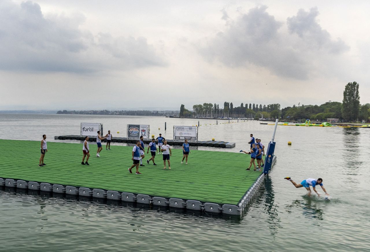 A rugby player scores a try while jumping into Lake Leman during a Water Rugby event commemorating the 50th anniversary of the Lausanne University Club rugby section in Lausanne, Switzerland, on Friday, August 19. Teams of five players compete on a floatable pitch measuring 25 by 35 meters. 