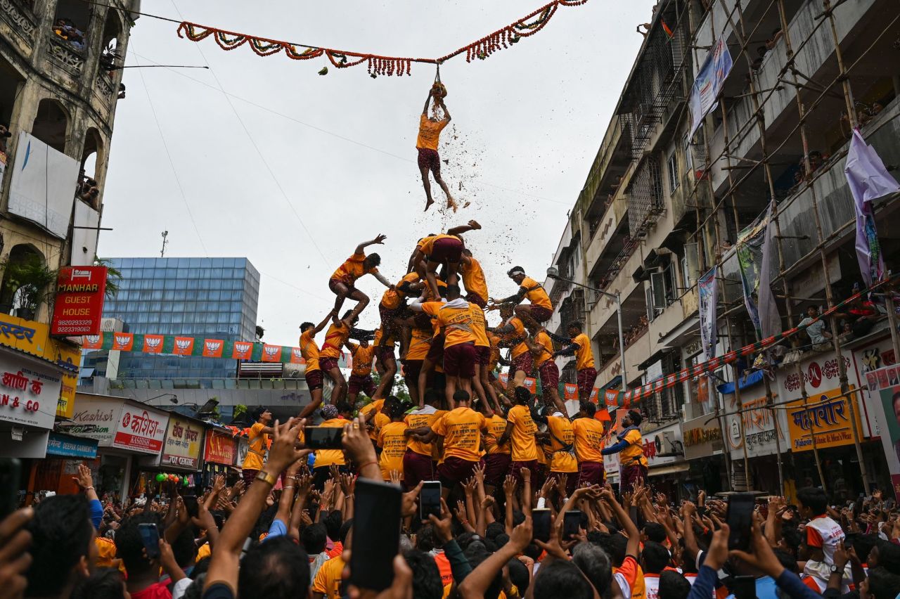 A young Hindu devotee hangs onto a rope suspended in the air as a human pyramid collapses beneath him during Janmashtami festival celebrations in Mumbai, India, on Friday, August 19.