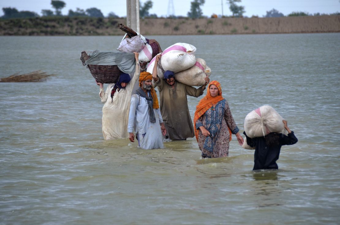 A displaced family wades through a flooded area in Jaffarabad, a district of Pakistan's southwestern Baluchistan province, on August 24.