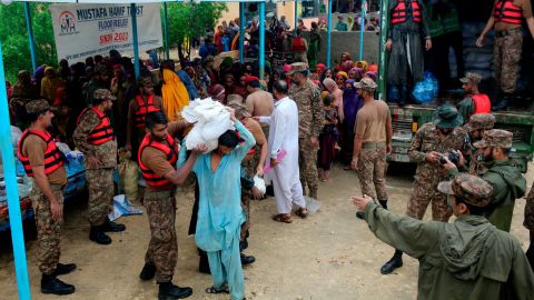 جنود من الجيش يوزعون مواد غذائية وإمدادات على نازحين في معسكر مساعدات في منطقة جامشورو ، جنوب باكستان ، في 24 أغسطس / آب.