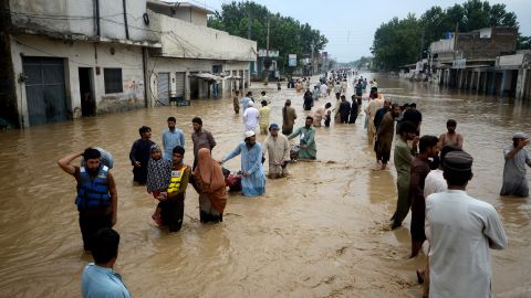 Displaced people wade through a flooded area in Peshawar, Khyber Pakhtunkhwa, Pakistan on Saturday.
