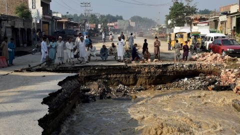 Des habitants se rassemblent à côté d'une route endommagée par les eaux de crue à la suite de fortes pluies de mousson dans le district de Charsadda à Khyber Pakhtunkhwa le 29 août 2022.