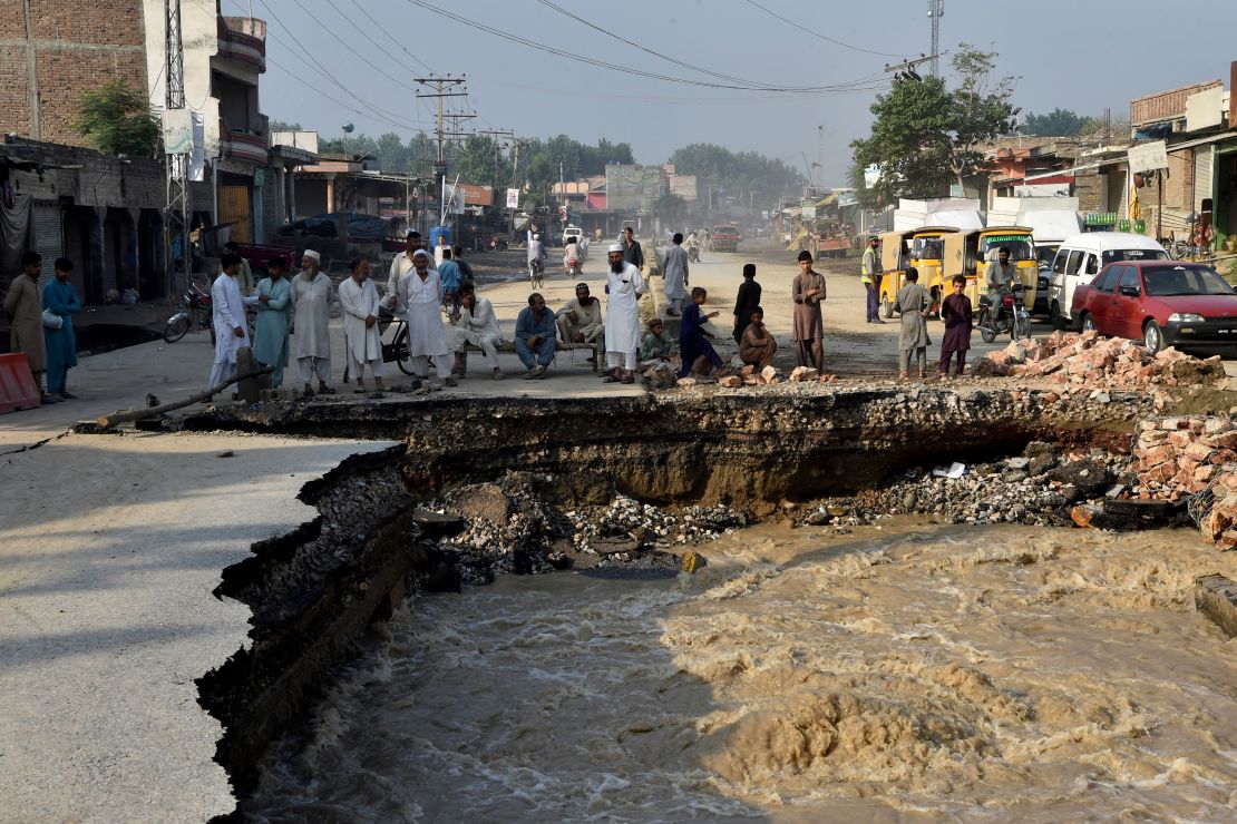 Residents gather beside a road damaged by flood waters following heavy monsoon rains in Charsadda district of Khyber Pakhtunkhwa on August 29, 2022.