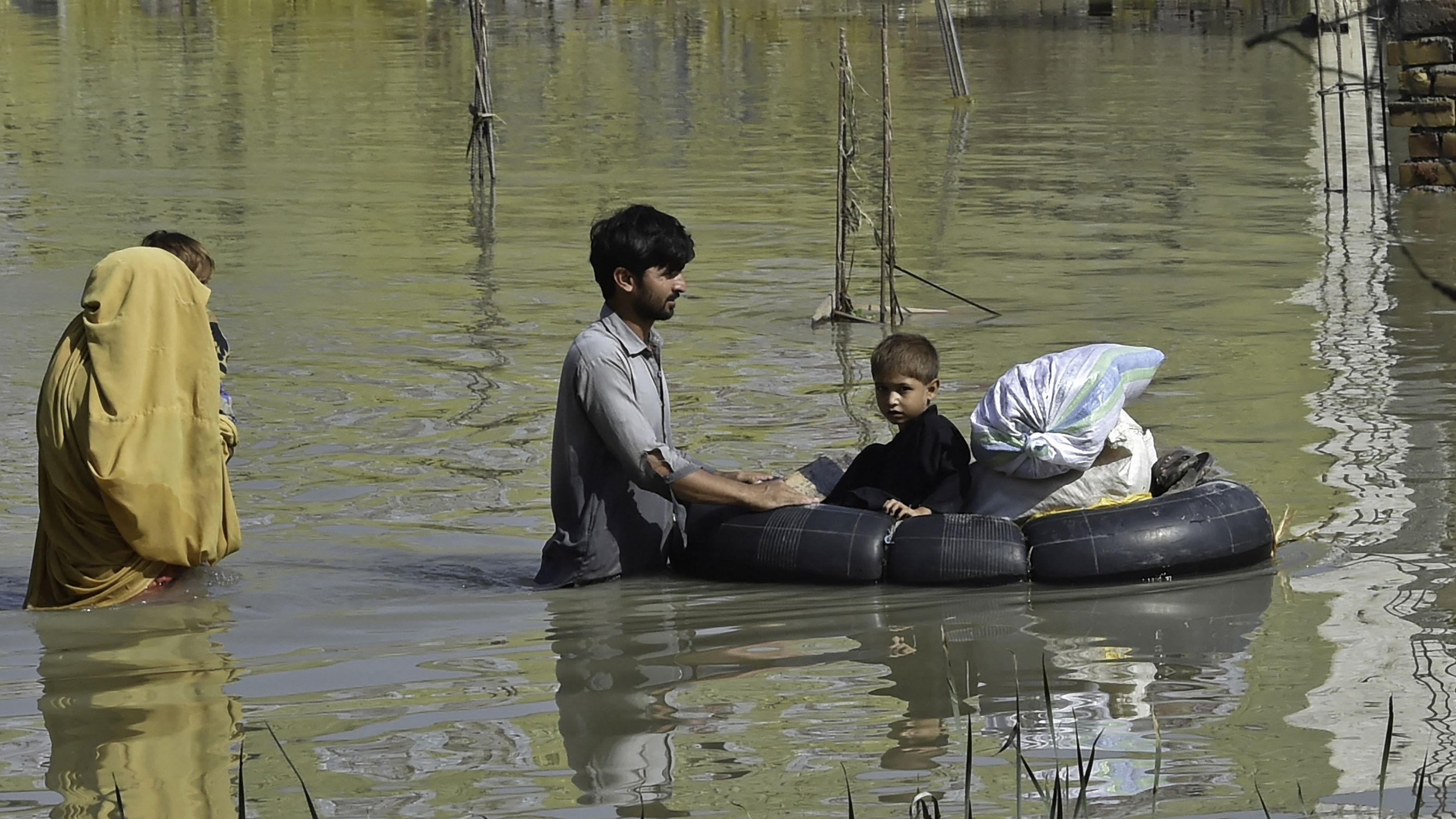 A family wades through a flood-hit area following heavy monsoon rains in Charsadda district of Khyber Pakhtunkhwa on August 29, 2022.