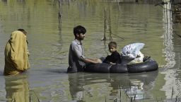 A family wades through a flood hit area following heavy monsoon rains in Charsadda district of Khyber Pakhtunkhwa on August 29, 2022. - The death toll from monsoon flooding in Pakistan since June has reached 1,061, according to figures released on August 29, 2022, by the country's National Disaster Management Authority. (Photo by Abdul MAJEED / AFP) (Photo by ABDUL MAJEED/AFP via Getty Images)