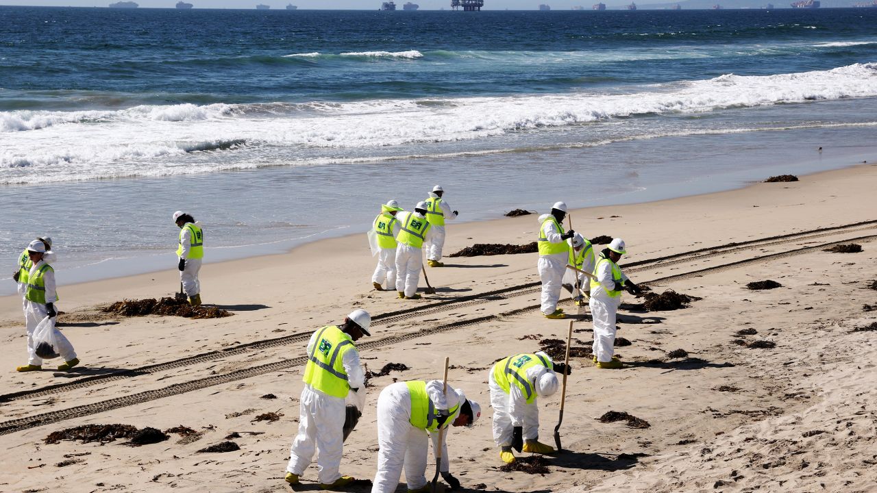Cleanup workers search for contaminated sand and seaweed along the mostly empty Huntington Beach, California, about a week after an oil spill in October 2021.