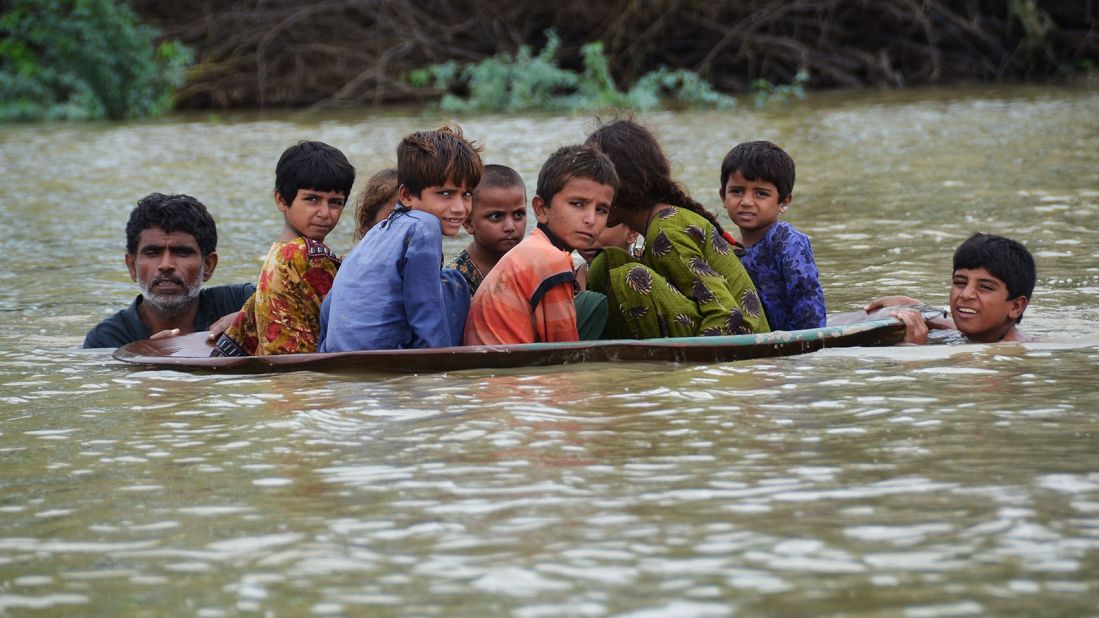 A man helps children navigate floodwaters using a satellite dish in Balochistan, Pakistan, on August 26.