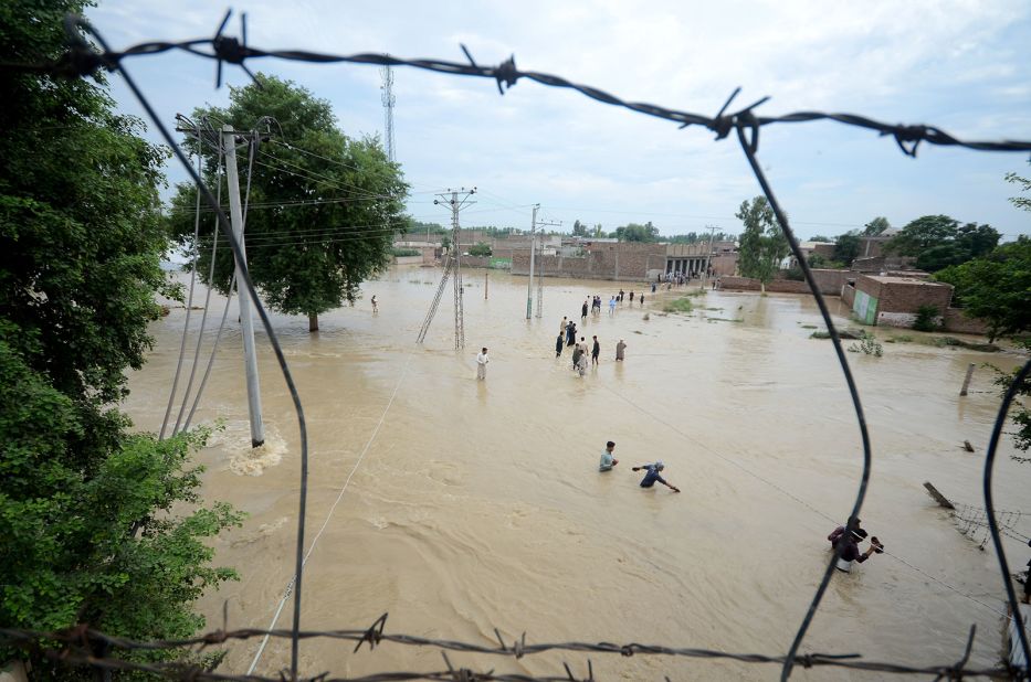 Displaced people wade through a flooded area in Peshawar, Pakistan, on August 27.