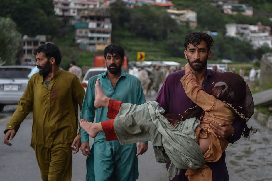 A man carries his sick daughter along a road damaged by floodwaters in Pakistan's northern Swat Valley on August 27.