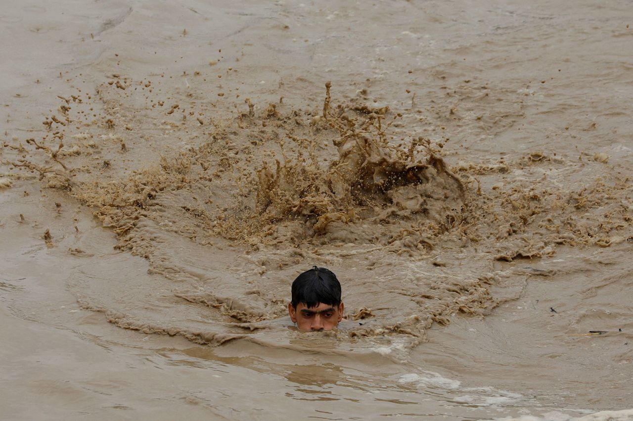 A man swims in floodwaters while heading for higher ground in Charsadda on August 27.