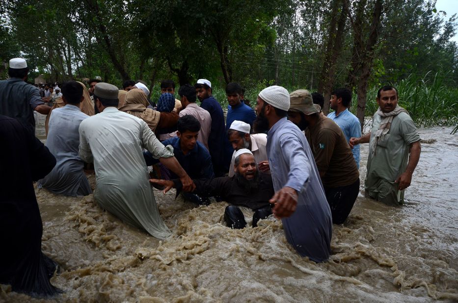 People walk through floodwaters in Dagai Mukram Khan, Pakistan, on August 26.