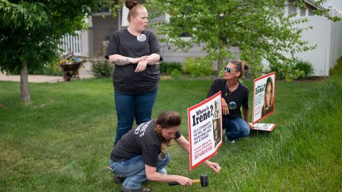 Lacey Ayers talks to Stacy Koester, left, and Melissa Bloxom as they place signs with an image of Irene Gakwa in a yard in Gillette, Wyoming. Gakwa lived with her boyfriend next door. 