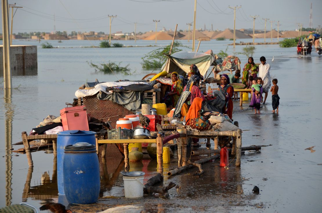 Families sit near their belongings inundated by flood waters in Pakistan's southwestern Balochistan province on August 28, 2022.