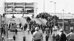 State troopers watch as marchers cross the Edmund Pettus Bridge over the Alabama River in Selma, Alabama as part of a civil rights march on March 9. Two days before troopers used excessive force driving marchers back across the bridge, killing one protester.