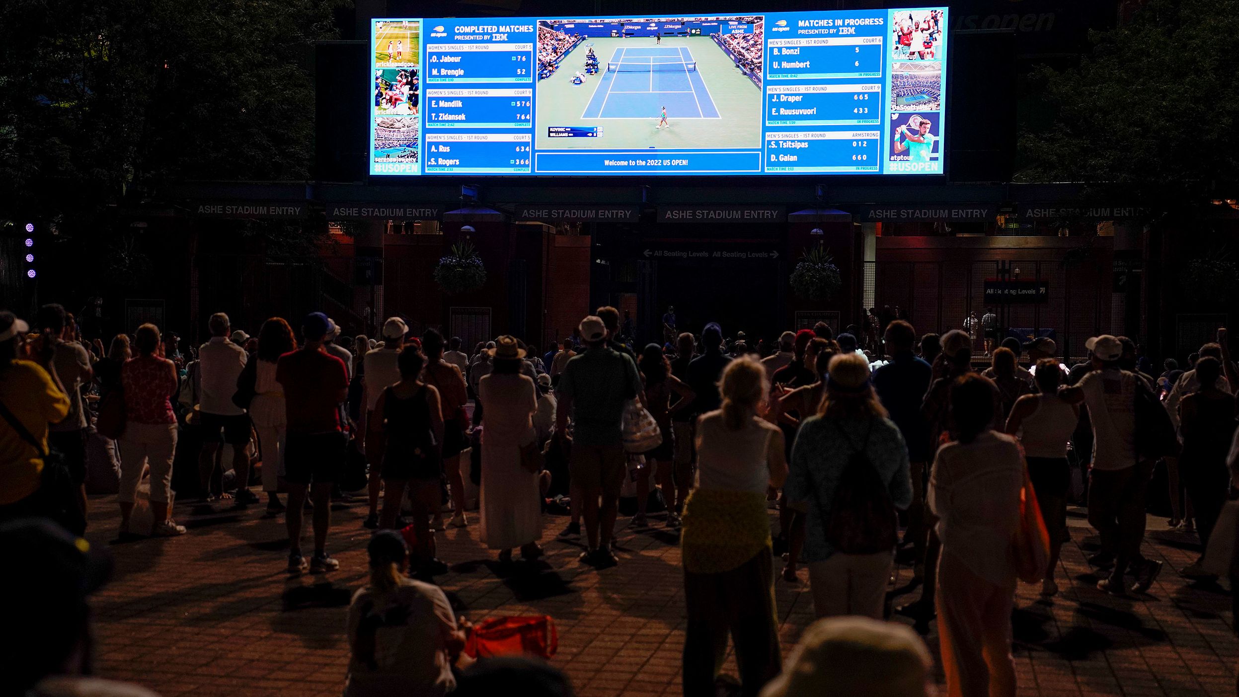 Fans outside the stadium watch the Williams match on a video screen Monday.