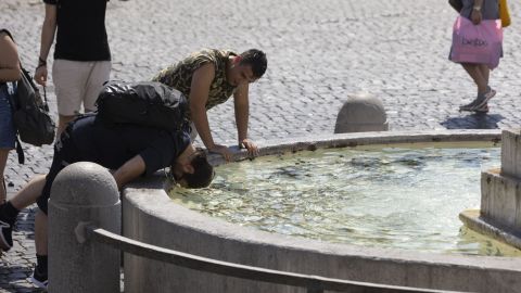 People cool off at a fountain in Piazza del Popolo in Rome in early August.