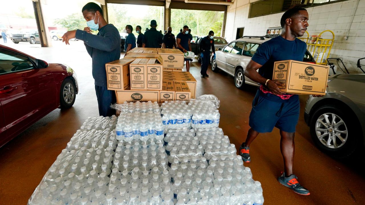 Firefighters and recruits for the Jackson Fire Department carry cases of bottled water to residents vehicles, August 18, 2022, as part of the city's response to longstanding water system problems.