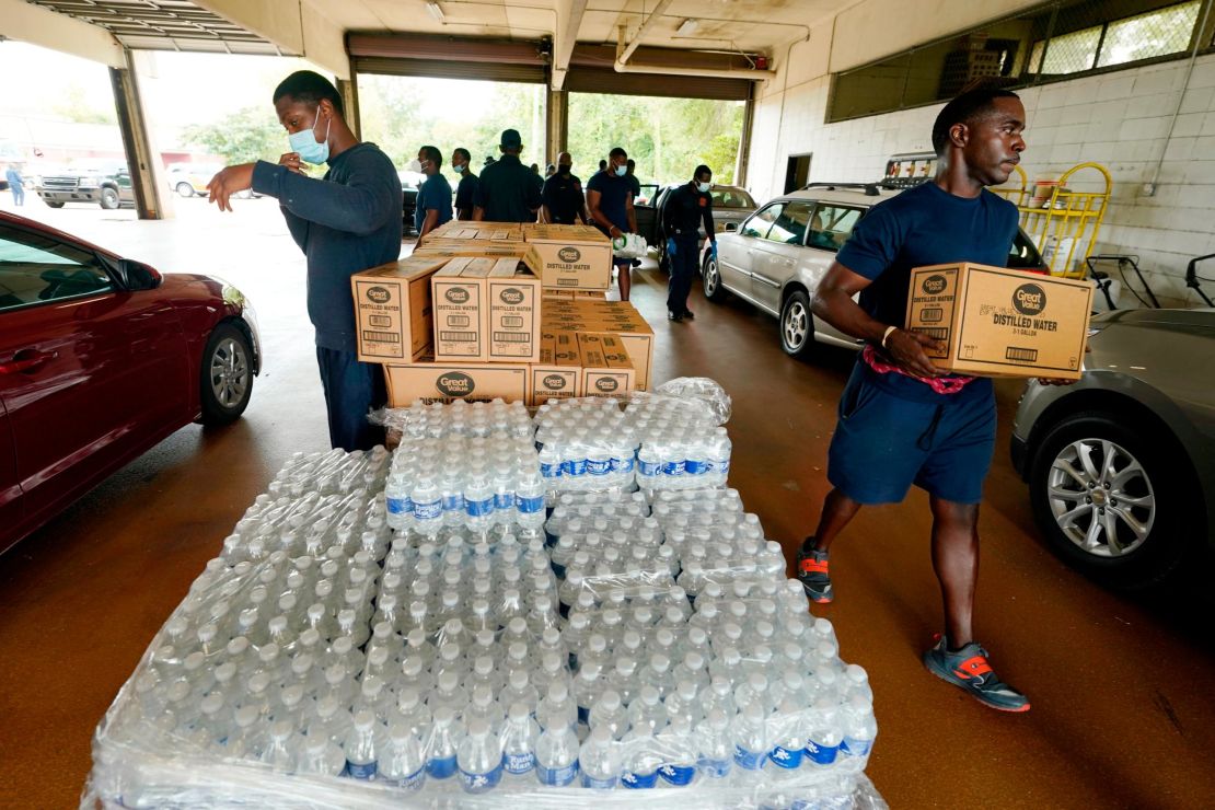 Firefighters and recruits for the Jackson Fire Department carry cases of bottled water to residents vehicles, August 18, 2022, as part of the city's response to longstanding water system problems. 