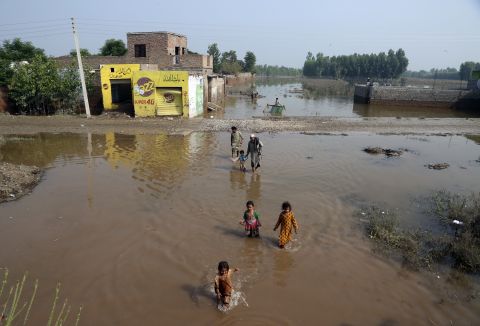 People wade through floodwaters in Charsadda, Pakistan, on August 31.