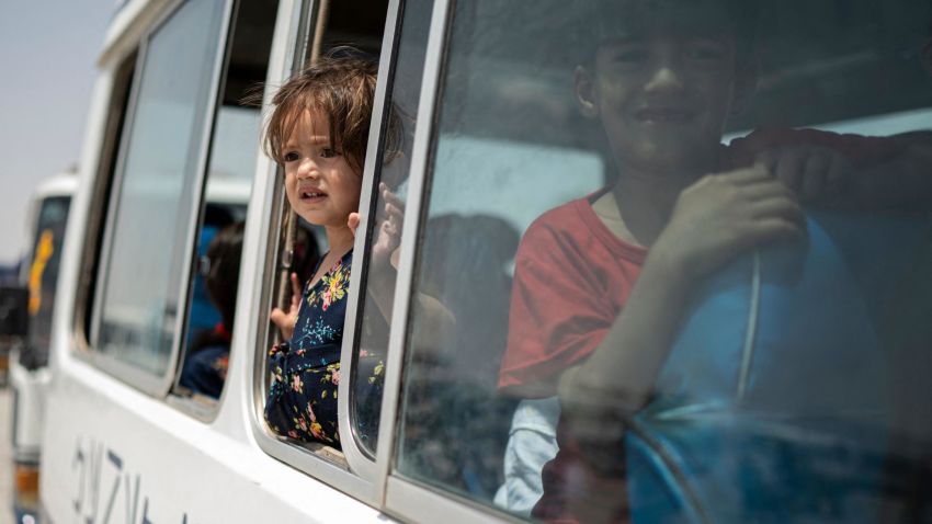 Afghan internally displaced children look out from a window of a bus as they return home to the east, at the United Nations High Commissioner for Refugees (UNHCR) camp in the outskirts of Kabul on July 28, 2022. - Hundreds of internally displaced Afghans who had taken refuge in the capital left for their homes in the country's eastern provinces Thursday, almost a year after the war that forced them to flee ended. (Photo by Wakil KOHSAR / AFP) (Photo by WAKIL KOHSAR/AFP via Getty Images)