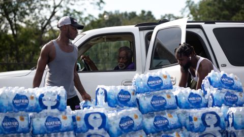 Quad Johnson, left, and Island Williams carry water Wednesday to a vehicle at a water distribution center at Grove Park Community Center in Jackson, Mississippi.