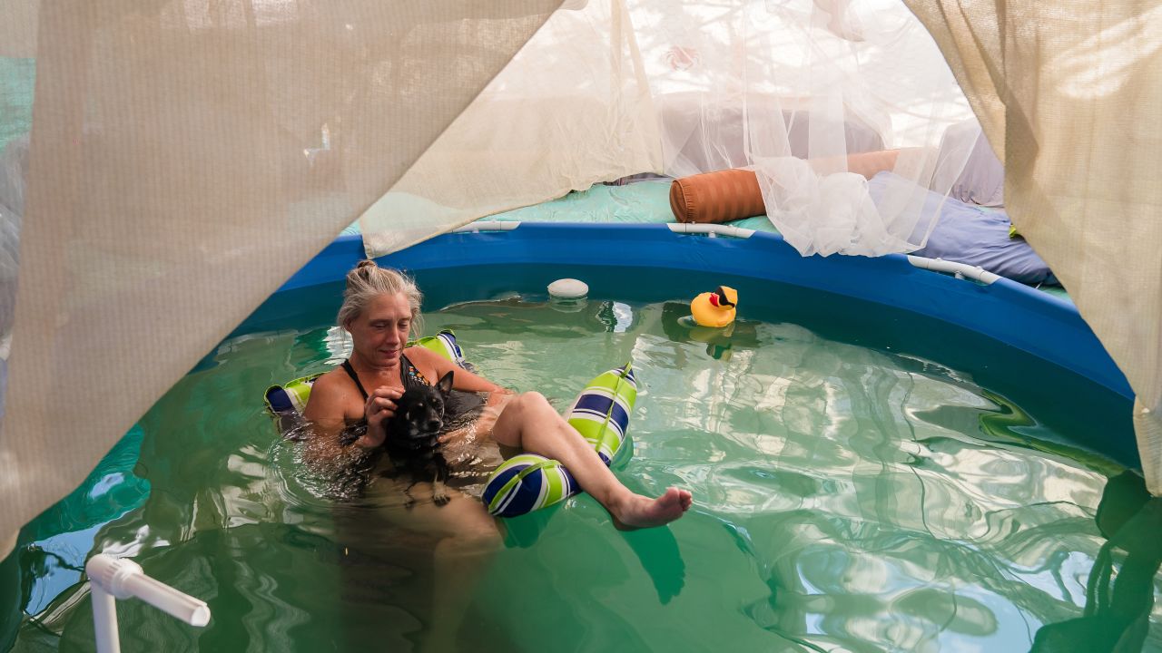 Dot of House of Dots art gallery relaxes in her pool with her dog as they cool off amid a heatwave on Wednesday in Slab City near Niland, California.