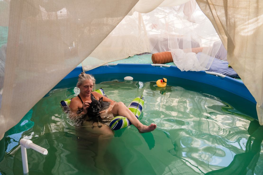 Dot of House of Dots art gallery relaxes in her pool with her dog as they cool off amid a heatwave on Wednesday in Slab City near Niland, California. 