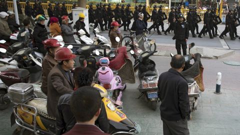 Residents watch a convoy of security personnel armed with batons and shields patrolling through Kashgar, Xinjiang, on November 5, 2017.
