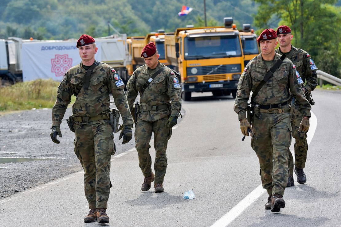 Polish soldiers, part of a NATO peacekeeping mission in Kosovo, pass through barricades near the border crossing between Kosovo and Serbia on September 28, 2021.